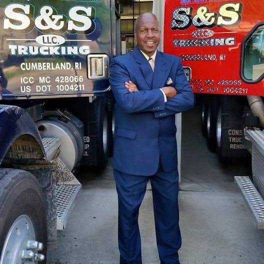 A man standing in front of two trucks.