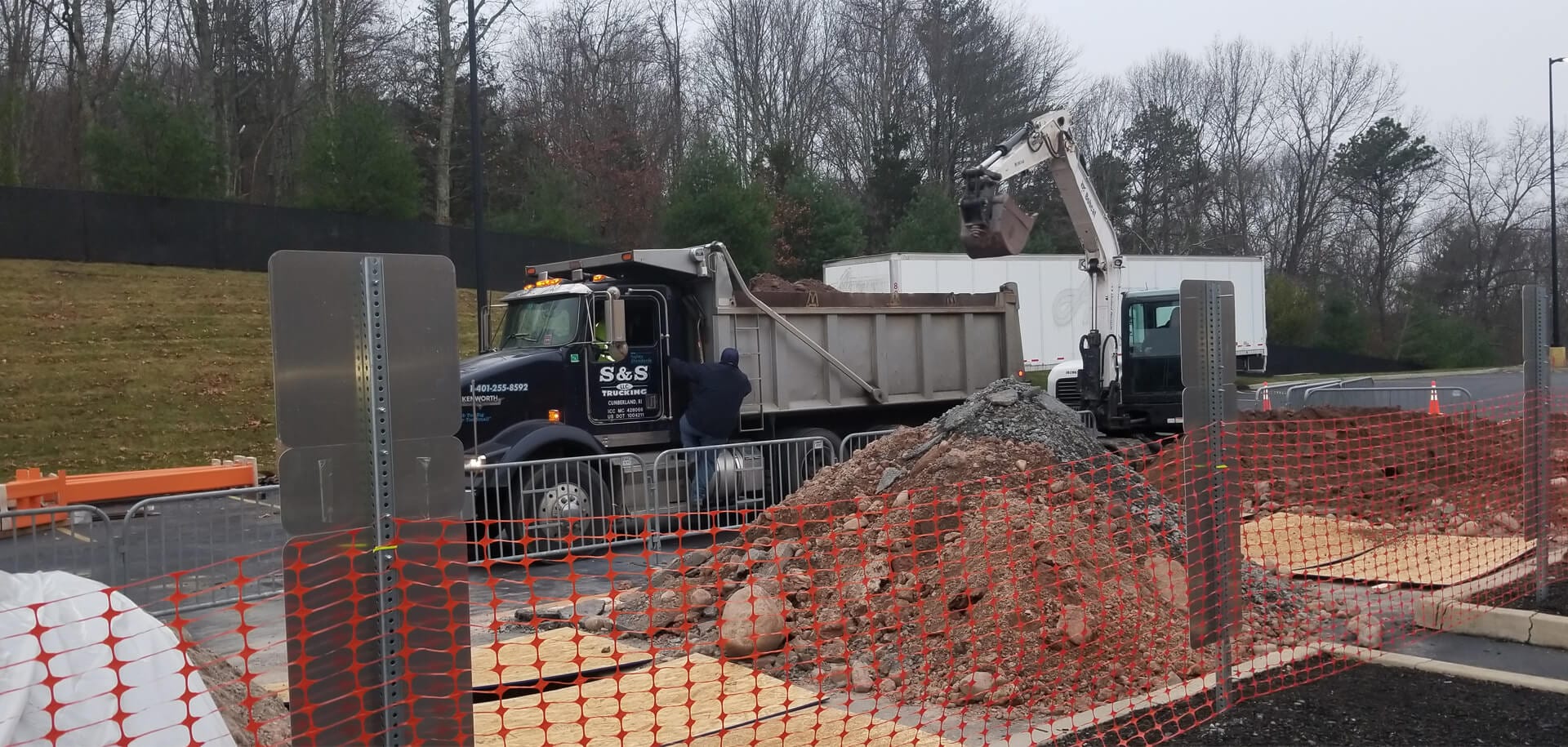 A dump truck is parked next to some dirt.